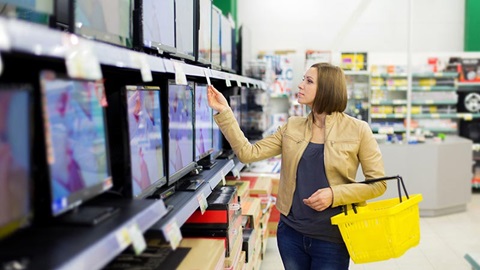 Vrouw kiest een nieuwe tv in de winkel